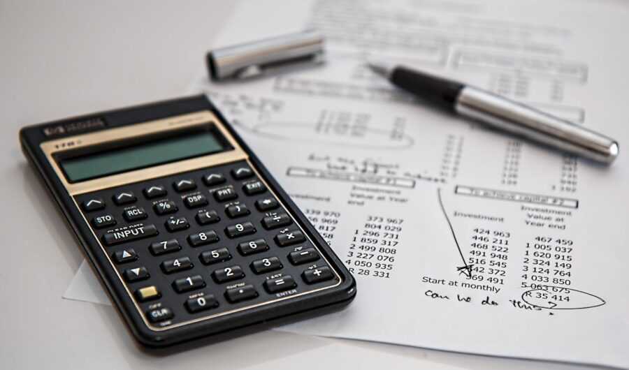 A calculator, a piece of paper, and a pen on a white surface.