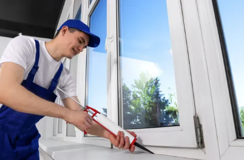 A caulking specialist sealing gaps around a window to improve home energy efficiency.